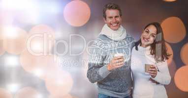 Happy couple holding disposable cups over bokeh