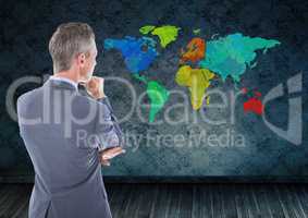 Businessman thinking looking at Colorful Map with wall room background