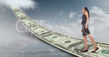 Digital composite image of businesswoman walking on money walkway leading towards sky