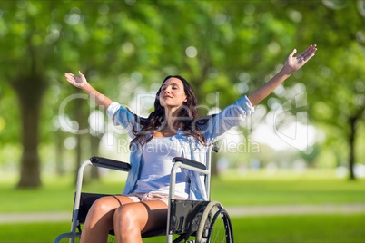 Woman with arms outstretched sitting on wheelchair at field