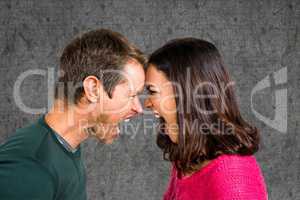 Side view of couple shouting while fighting against gray background