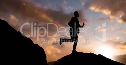 Silhouette businessman running on mountain against sky during dusk