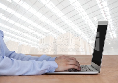 Man on laptop with bright warehouse background