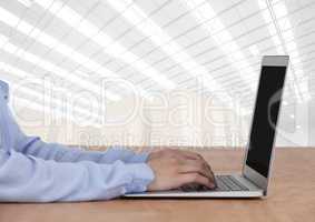 Man on laptop with bright warehouse background