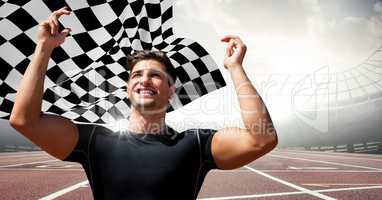 Male runner with hands in air on track against flares and checkered flag