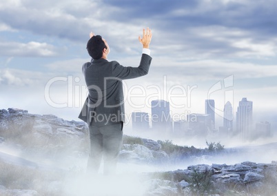 Business man hands up on misty mountain peak against skyline