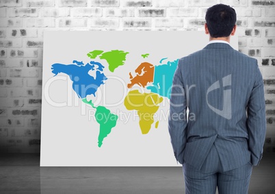Businessman looking at Colorful Map with brick wall background