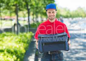 Pizza deliveryman with blue hat and delivery bag in the park