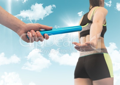 Relay runner and hand with blue baton against sky with flares