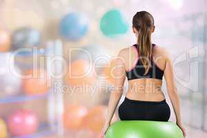 Rear view of woman sitting on fitness ball at gym