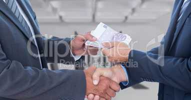 Midsection of corrupt businessmen holding money while shaking hands