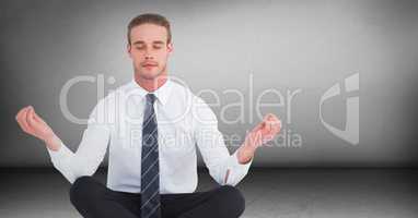 Business man meditating in grey room