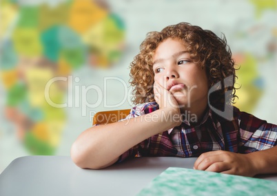 Bored boy at desk against blurry map