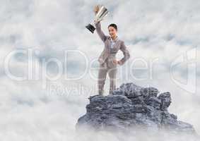 Business woman with trophy on mountain peak in the clouds