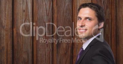 Smiling businessman over wooden wall