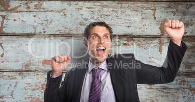 Happy businessman celebrating success against wooden wall