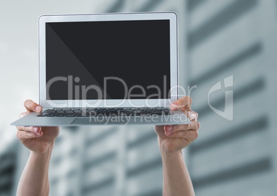 Hands with laptop against blurry building