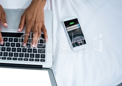 phone with log in screen and laptop with hands on the bed