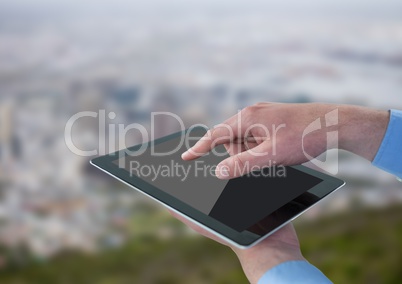 Hands with tablet against blurry skyline