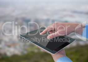 Hands with tablet against blurry skyline