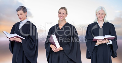 Women Judges holding books in front of sky clouds