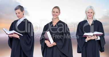 Women Judges holding books in front of sky clouds