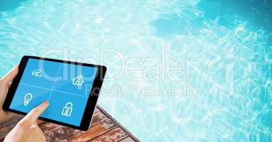 Hands touching icons on digital tablet's screen by swimming pool