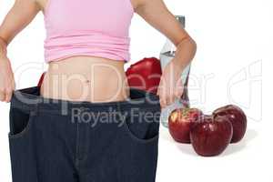 Midsection of woman wearing loose jeans with fruits by drink and boxing gloves in background