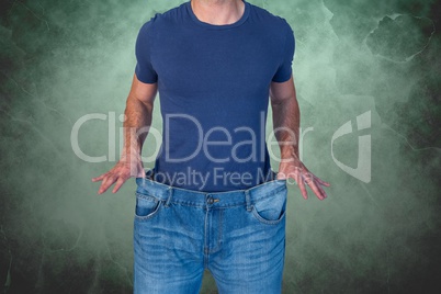 Midsection of man wearing loose jeans against green background