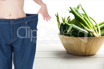 Midsection woman in loose jeans by vegetables