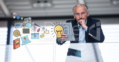 Businessman holding tablet PC with idea icons in foreground