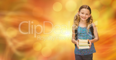Smiling girl holding books against blur background