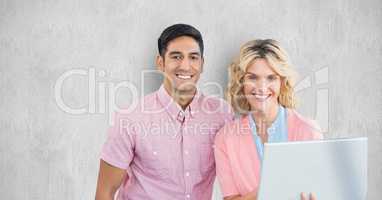 Smiling business people with laptop against wall