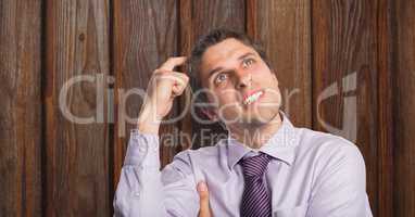 Businessman scratching head over wooden wall