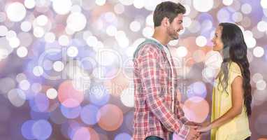 Side view of couple holding hands over blur background