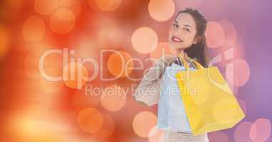 Smiling woman carrying shopping bags over blur background