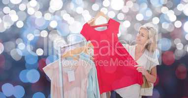 Smiling woman holding red dress over bokeh