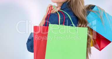 Midsection of woman holding shopping bags against white background