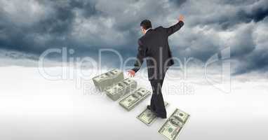 Businessman walking on money steps in sky