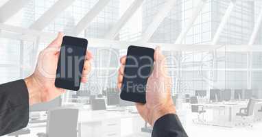 Cropped image of hands holding smart phones in office