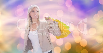 Woman looking away while carrying shopping bags over bokeh