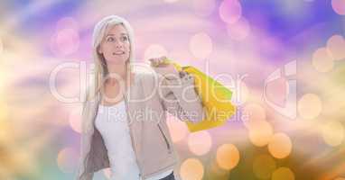 Woman looking away while carrying shopping bags over bokeh