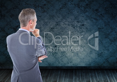 Businessman looking at grunge wall in room