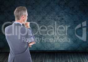 Businessman looking at grunge wall in room