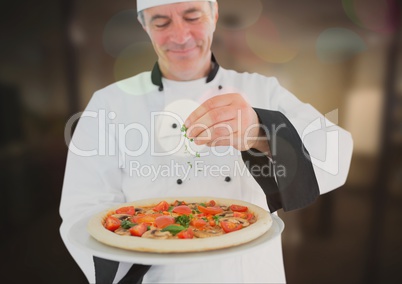 Chef pouring oregano to the pizza in the restaurant