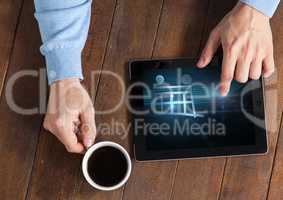 Person using Tablet with Shopping trolley icon and coffee
