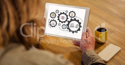 High angle view of woman looking at gears in digital tablet