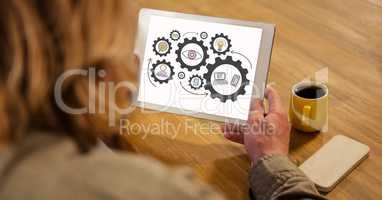 High angle view of woman looking at gears in digital tablet