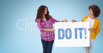 Female friends holding billboard with do it text against blue background