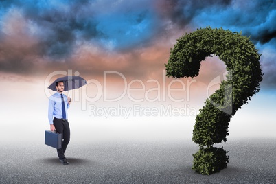 Digital composite image of businessman with umbrella and briefcase walking towards question mark mad